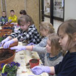 Dzieci sadzą roślinki do doniczek.