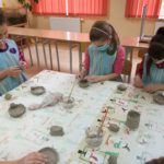 Dzieci wykonują miseczkę z gliny.