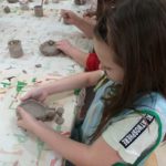 Dzieci wykonują miseczkę z gliny.