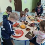 Dzieci przygotowują sałatkę owocową.