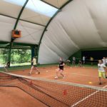 Dzieci grają na korcie tenisowym.