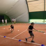 Dzieci grają na korcie tenisowym.