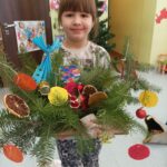 Dziewczynka prezentuje świąteczny stroik.