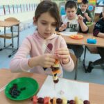Dzieci przygotowują owocowe lizaki.