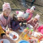 Dzieci jedzą kiełbaski.