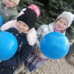 Dzieci z niebieskimi balonikami.