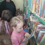 Dzieci w bibliotece słuchają opowieści i czytają książki.